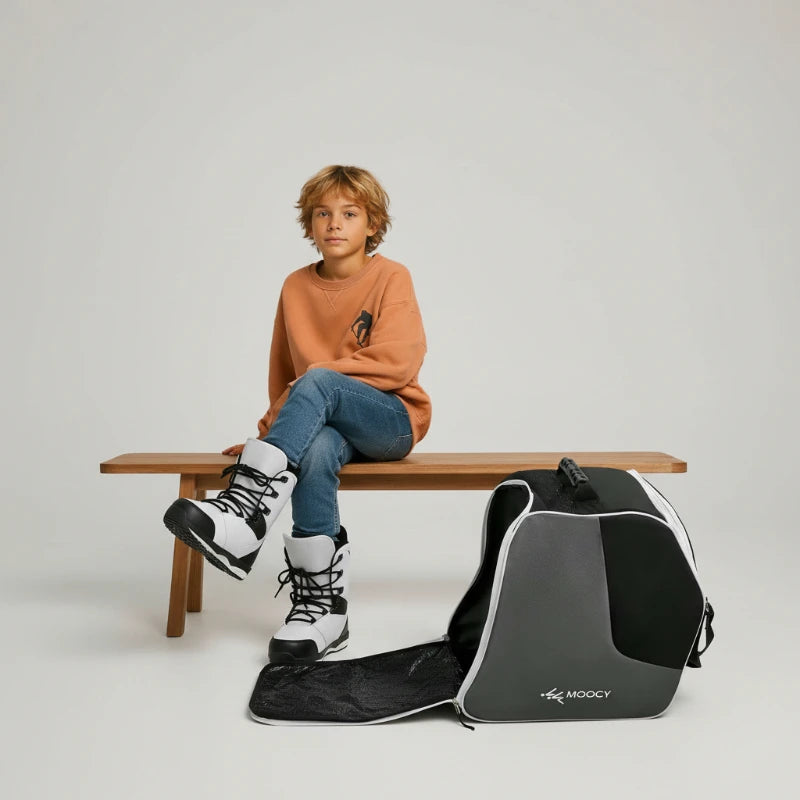 Enfant assis avec un sac de ski enfant contenant des chaussures de ski dans un compartiment séparé
