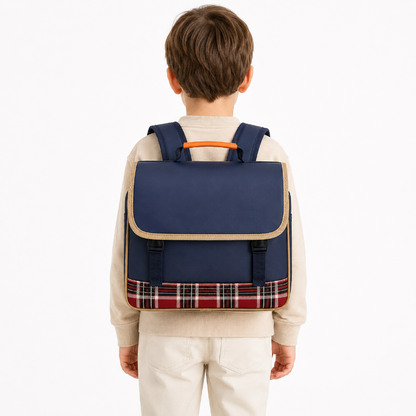 Enfant de primaire portant un cartable bleu marine avec bordures beige, poignée orange et bande écossaise rouge, vue de dos