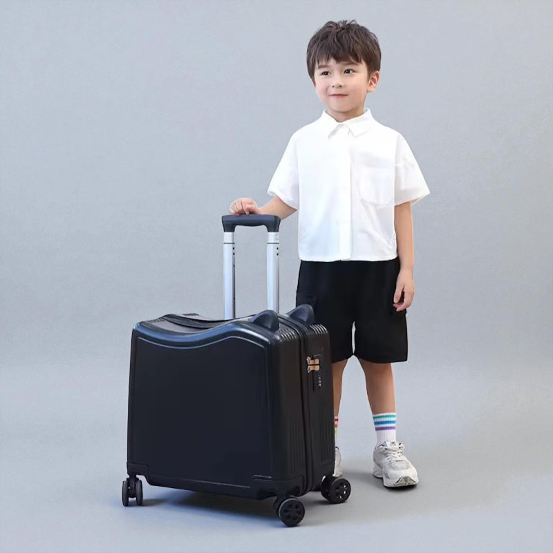 Petite valise enfant noire à roulettes tenue par un garçon en voyage