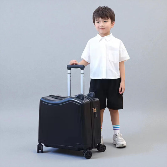 Petite valise enfant noire à roulettes tenue par un garçon en voyage
