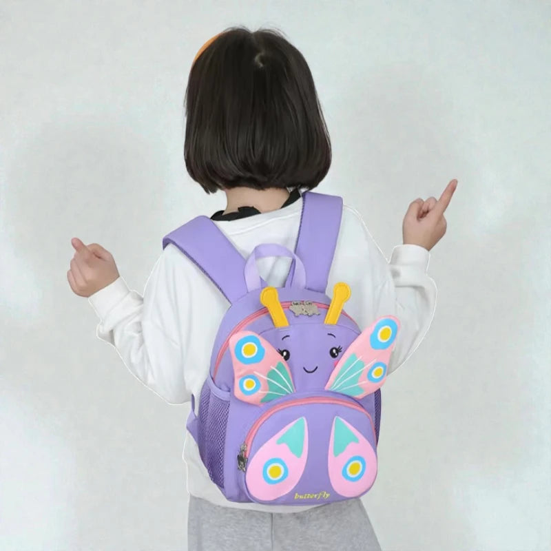 Vue arrière d’un sac à dos fille maternelle papillon violet porté par une enfant.
