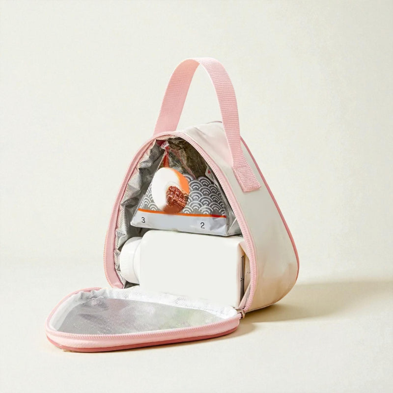 Intérieur du sac gouter isotherme rose, avec boisson et en-cas rangés dans la poche principale.